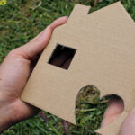 Two hands holding a cardboard house