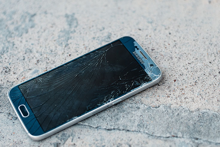 Broken mobile phone lying on concrete floor
