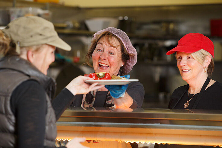 Two Meals Program volunteers handing out a plate to a client