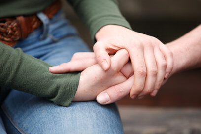Two people holding hands in support