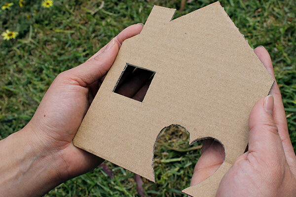 Hands holding a cardboard house
