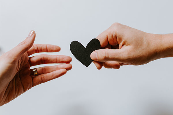 two-hands-holding-paper-heart Two hands holding a black paper heart