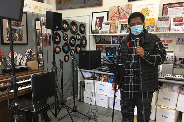 Rooming House Plus resident gives a live music performance wearing a face mask