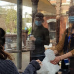 Meals Program staff in PPE members handing out a takeaway meal to a client during the pandemic