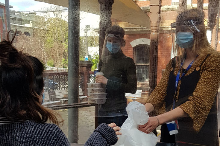 Two Meals Program staff in PPE handing out takeaway meals