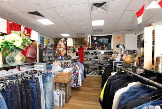 interior of Sacred Heart Mission Elsternwick Op Shop with racks of jeans to the left and blazers to the right, you can see all the way to the rear of the store where there is a shoe rack and a small library of books
