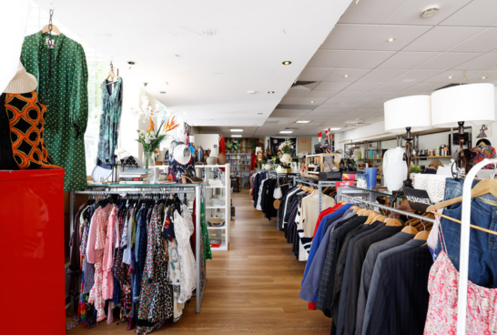 interior of Sacred Heart Mission Elsternwick Op Shop with racks of jeans to the left and blazers to the right, you can see all the way to the rear of the store where there is a shoe rack and a small library of books