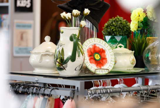 various vases some white with green next to a plate displayed with a big red flower in the centre