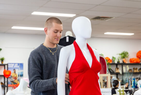 Elliot Garnaut dressing a mannequin inside the Commercial Rd op shop