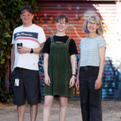 Three pathways workers smile in front of a colourful wall
