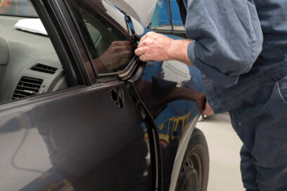 Person fitting a car panel at an auto repair shop