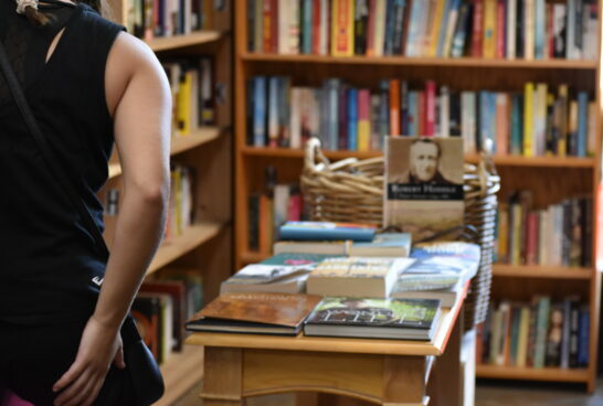 Person standing in front of a book shelf in our Prahran op shop