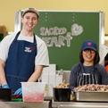 Two dining hall volunteers prepare food
