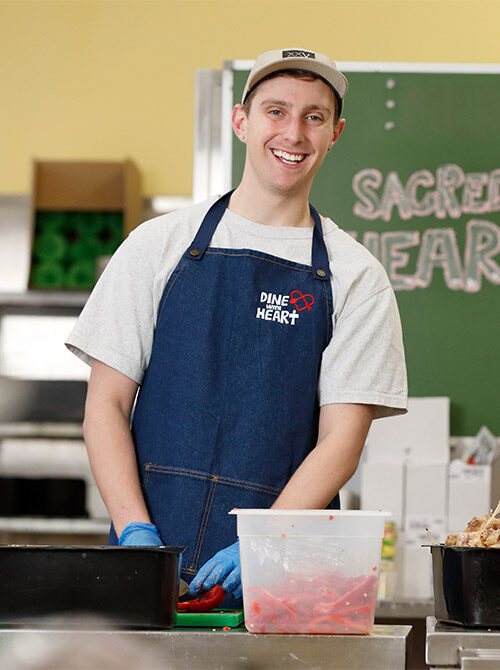 Volunteer smiling and chopping vegetables