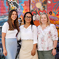 Three GreenLight Plus staff members in front of a colourful wall