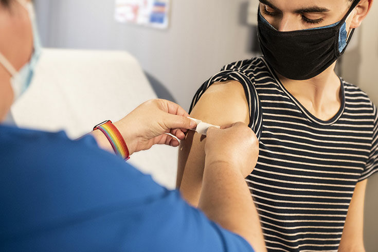 A health professional puts a band-aid on a patient's upper arm