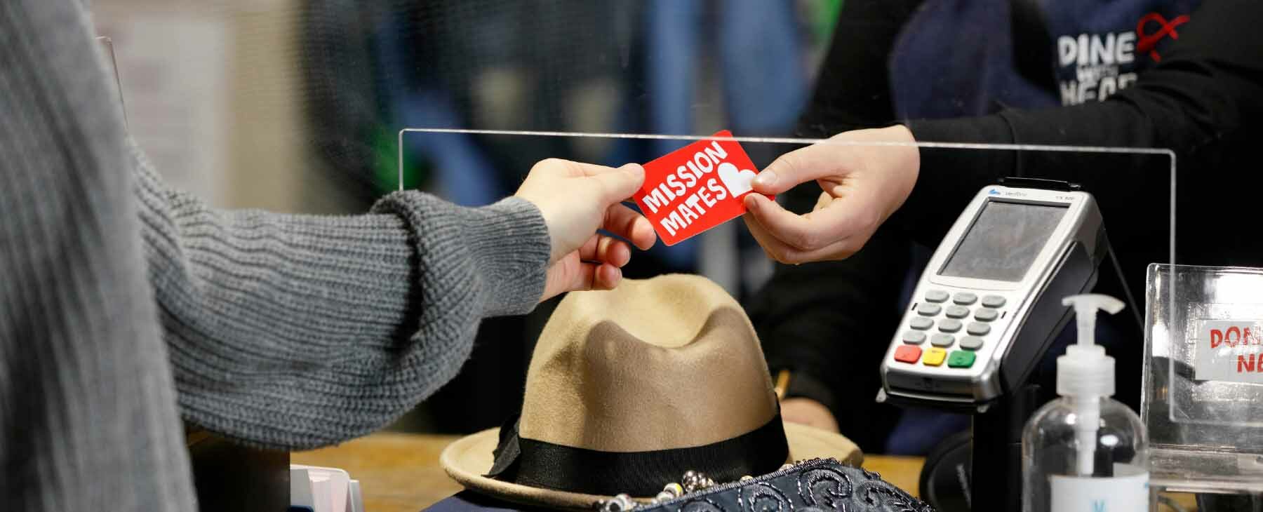 A customer hands their Mission Mates card