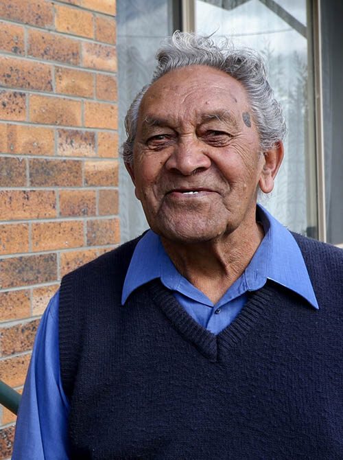 Elderly man standing outside of his home