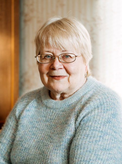 middle-aged woman wearing glasses and smiling into the camera