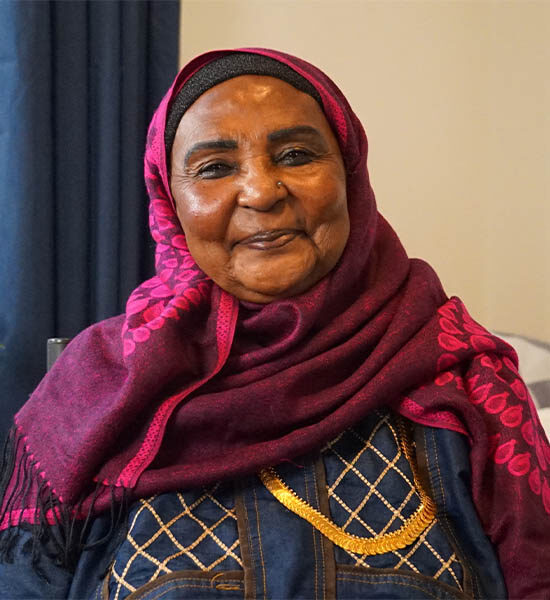 Woman wearing a purple hijab smiles friendly into the camera