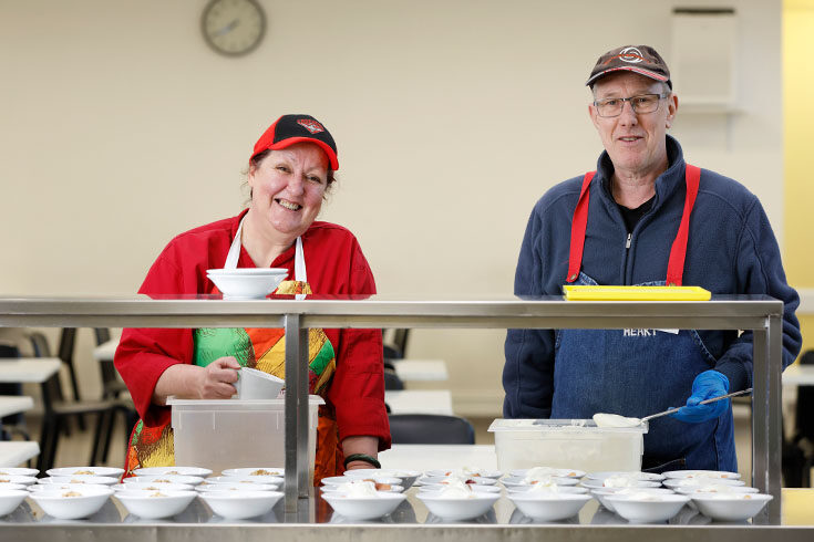 two-people-preparing-food-smiling Two people preparing food in our Dining Hall and smiling into the camera