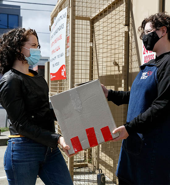 Woman hands over a cardboard box to an op shop staff member