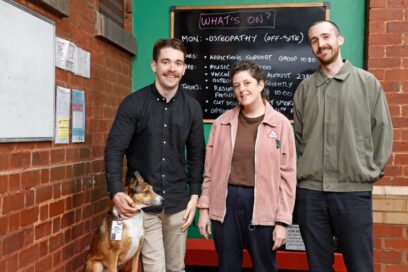 three staff members with a dog smiling into the camera