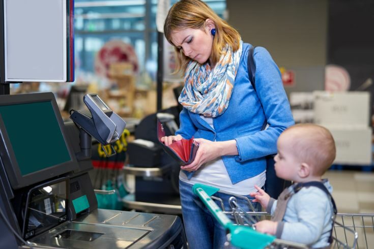 Mother with child paying at the supermarket checkout