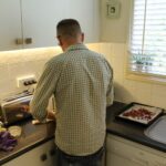 Man standing in a white kitchen with his back turned to the camera