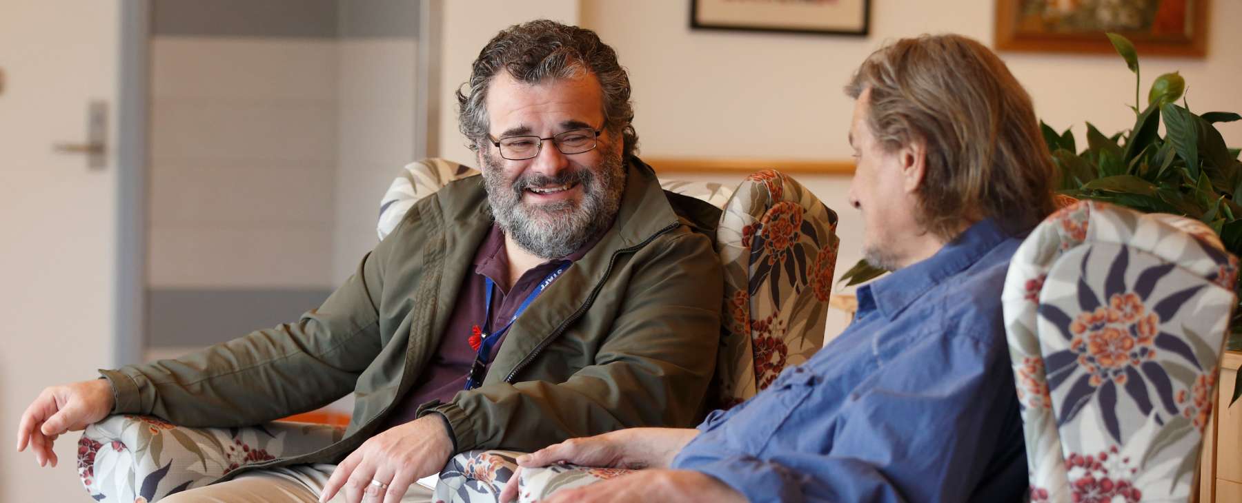 Two men sitting in armchairs and talking with each other