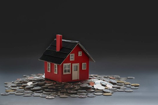 HouseBudget A toy house sits on a bed of coins