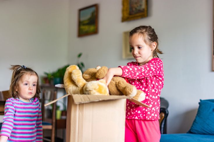Kids putting teddy bear into cardboard box