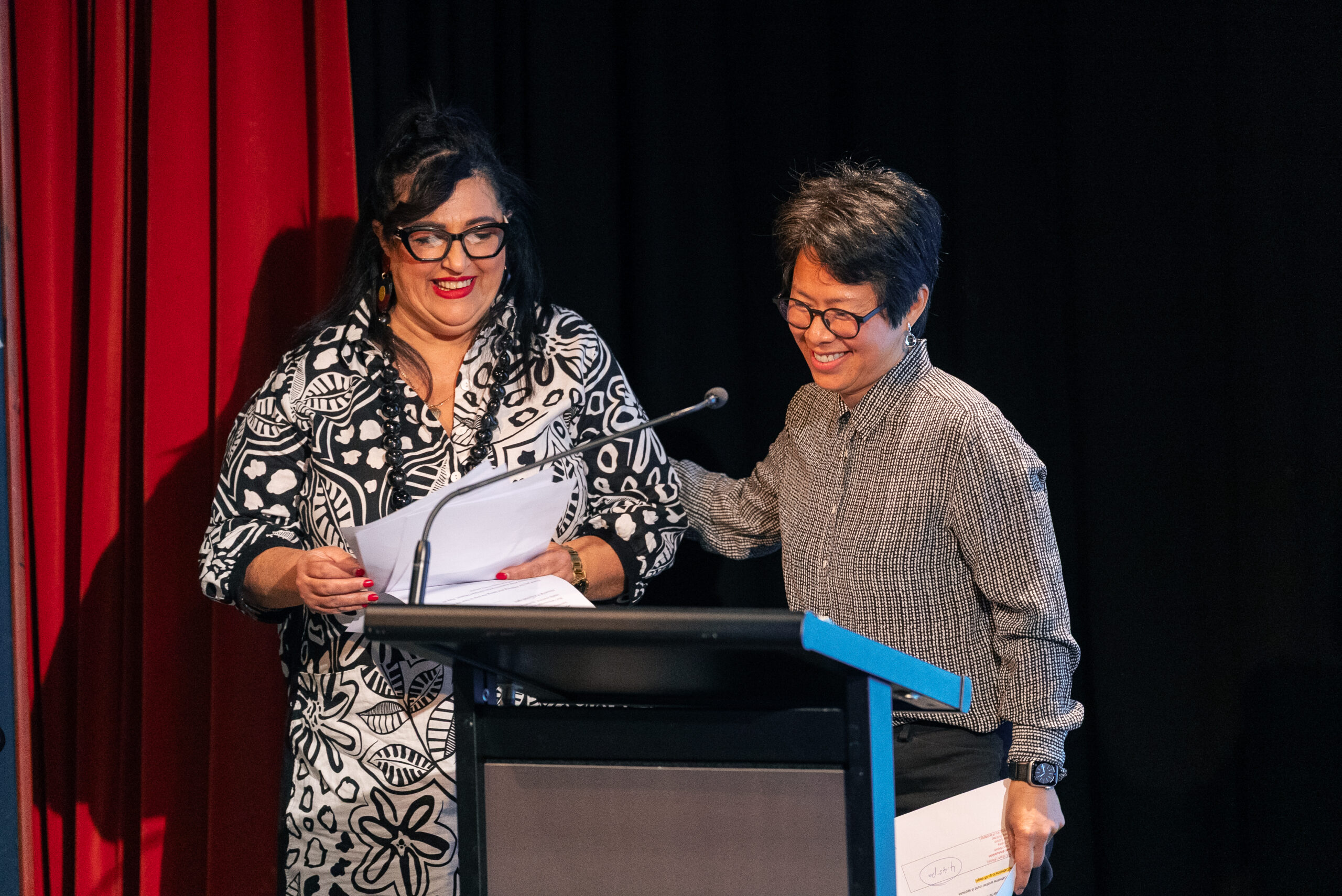 A woman on a stage is being congratulated for giving a speech by another women who is MCing the event.