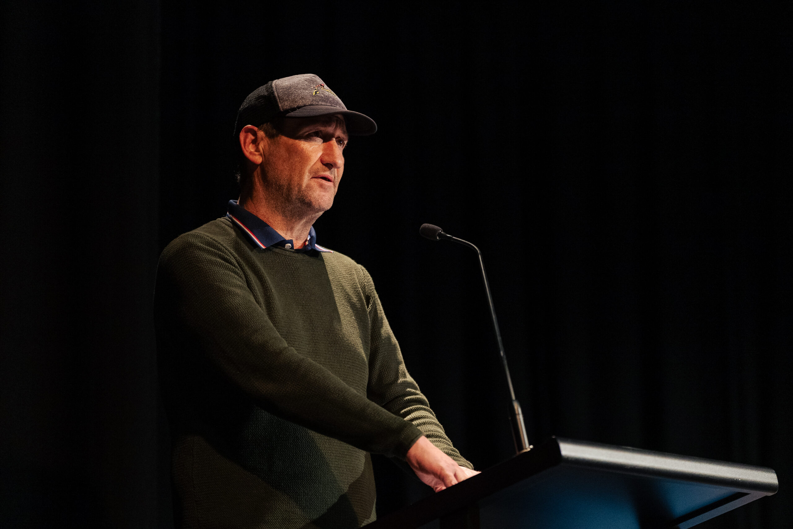 A man on a stage speaking at a lectern.