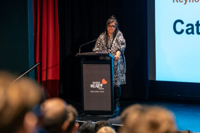 A woman standing at a lectern in front of an audience.
